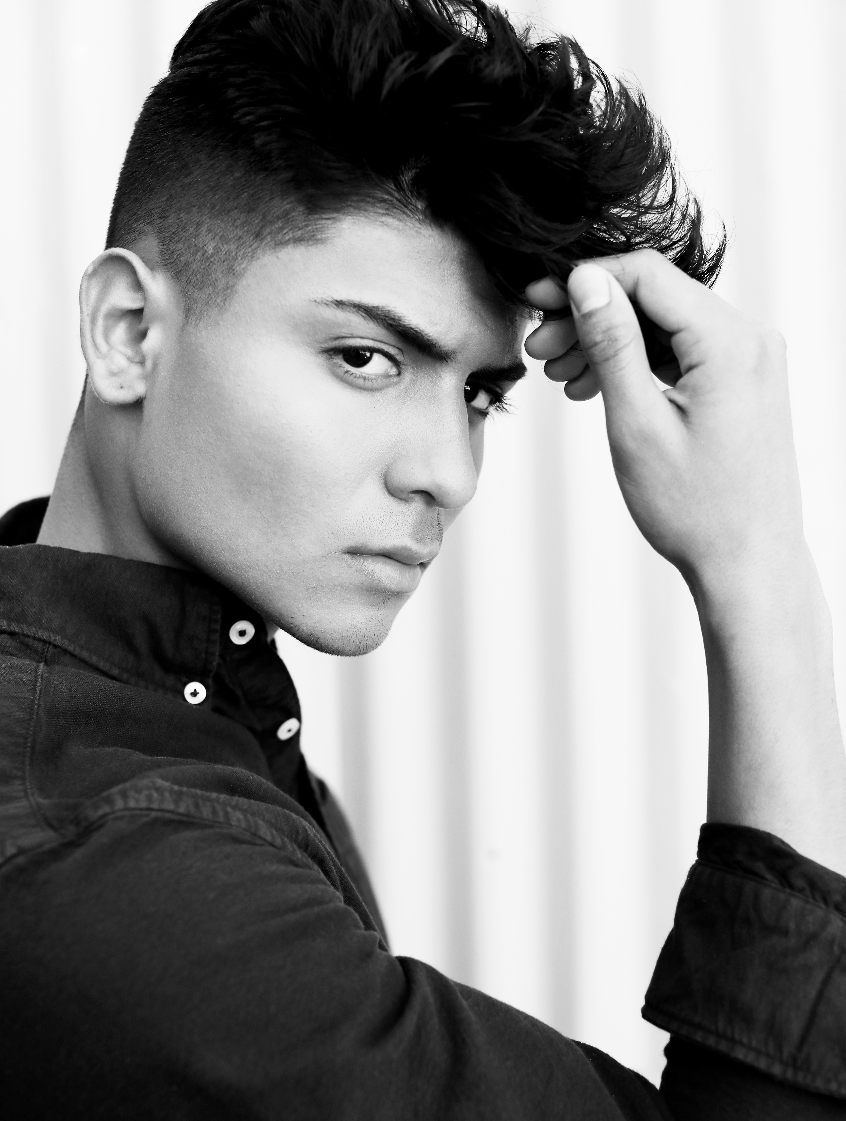 Black-and-white model portrait with a hand in his hair