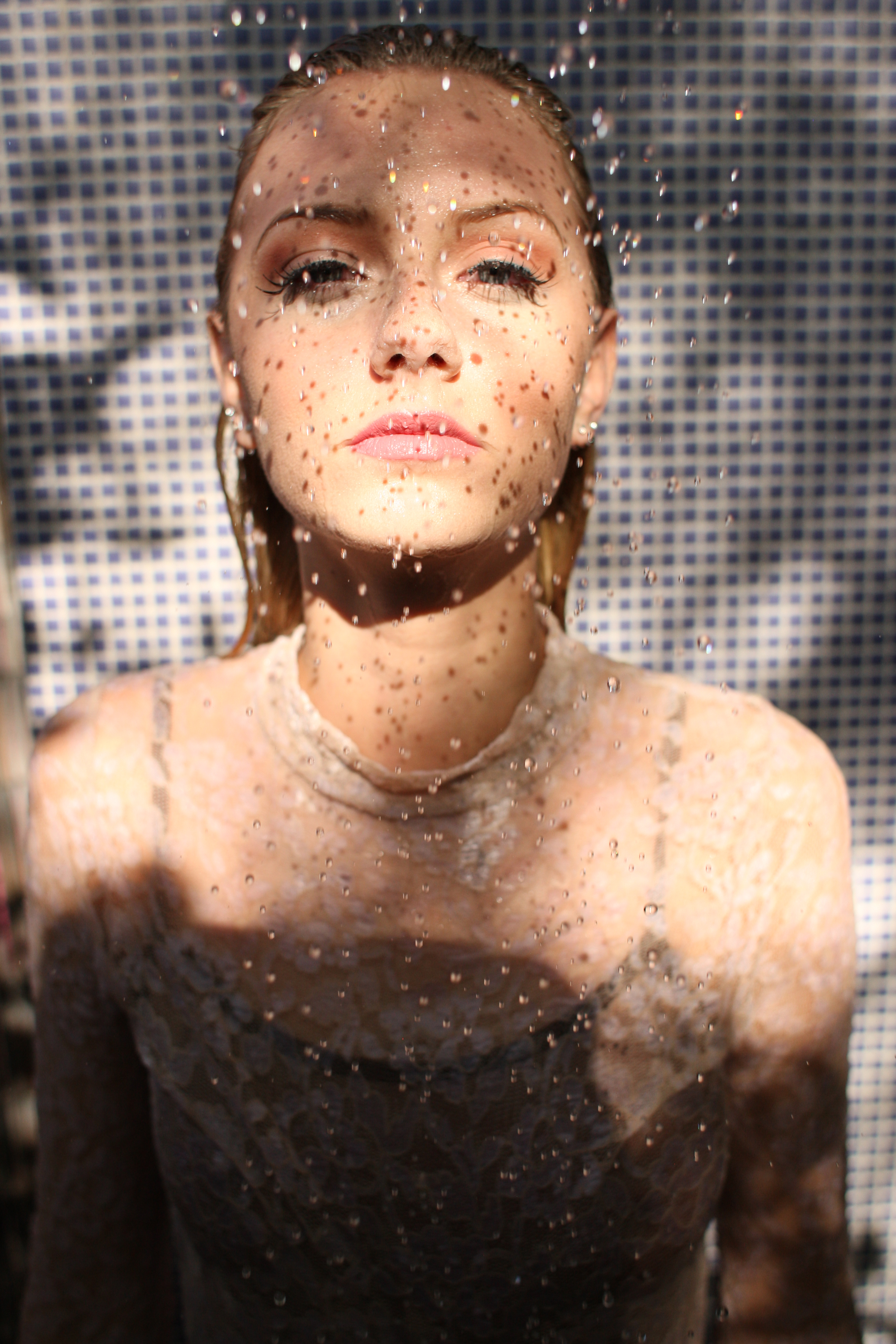 Beauty portrait with water droplets against a blue tiled background
